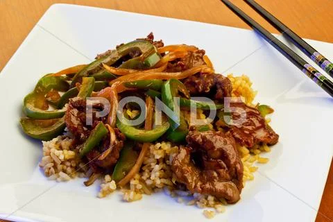 Beef with green pepper on a white plate with chopsticks. Stock Photos