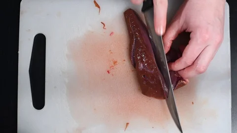 Beef liver on the table cut with a knife on a white cutting Board Stock Footage 103154524