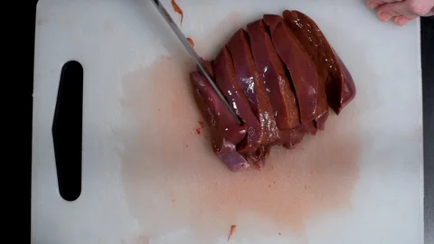 Beef liver on the table cut with a knife on a white cutting Board Stock-Footage 104864766