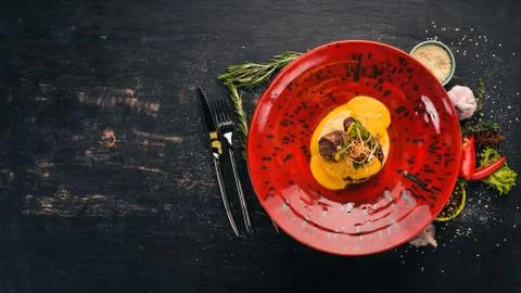 Beef loin with mashed couscous. Hot appetizers. Top view. On a black wooden b Stock Photos