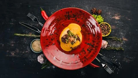 Beef loin with mashed couscous. Hot appetizers. Top view. On a black wooden b Stock Photos