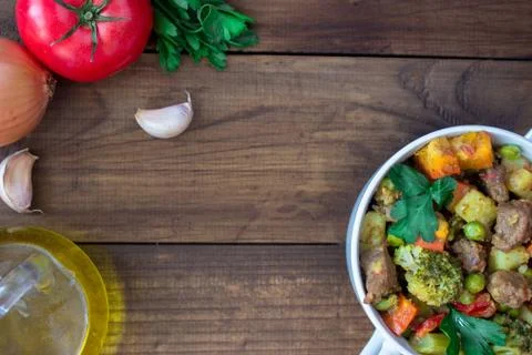 Beef meat stewed with vegetables in ceramic pot with ingredients on wooden Stock Photos