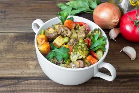 Beef meat stewed with vegetables in ceramic pot with ingredients on wooden Stock Photos