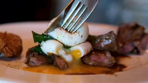 Beef medium steak cut egg benedict poached Female hands cutting poached egg Video stock 293339841