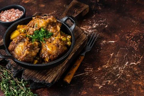Beef oxtails stew with wine and vegetables in a pan. Dark background. Top view Stock Photos
