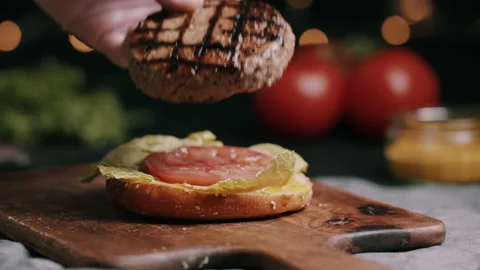 Beef Pattie Placed On Hamburger Bun With Lettuce And Tomato In The Kitchen Video stock 134409843