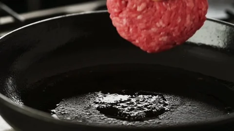 Beef patty gently placed in a hot cast iron pan Stock Footage 92150839