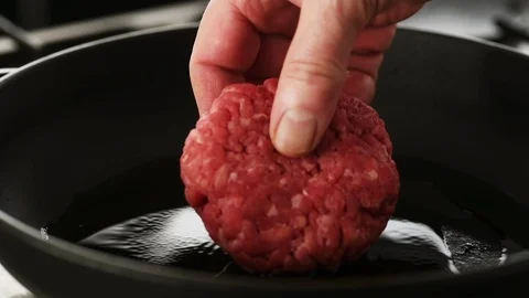 Beef patty gently placed in a hot cast iron pan Stock Footage 92150849