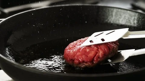 Beef patty gently turned in a hot cast iron pan Stock Footage 92150951