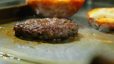 Beef patty for hamburger sizzles gently in hot oil Stock Footage 325024903