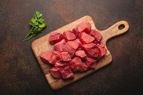 Beef raw meat cubes for stew on wooden cutting board Stock Photos