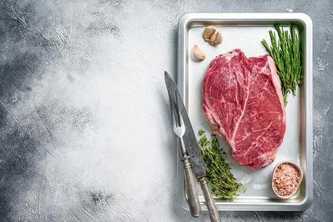 Beef raw steak cut in a baking dish. White background. Top view. Copy space Stock Photos