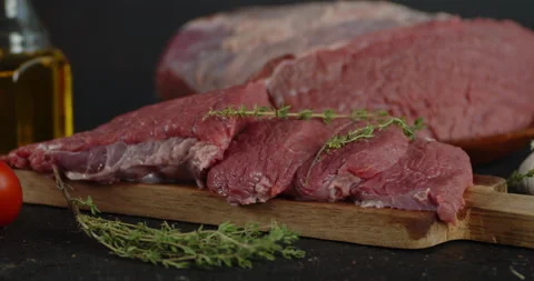 Beef raw with thyme slowly rotates on the table. Stock Footage 139157811