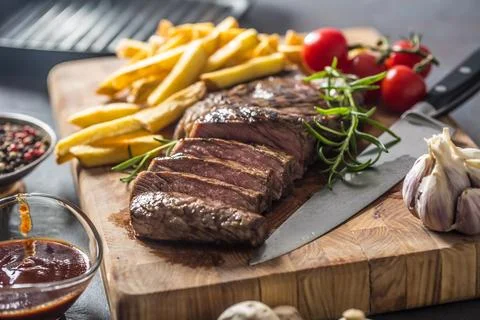 Beef Rib Eye steak with roasted potatoes bbq sauce garlic mushrooms and spice Stock Photos