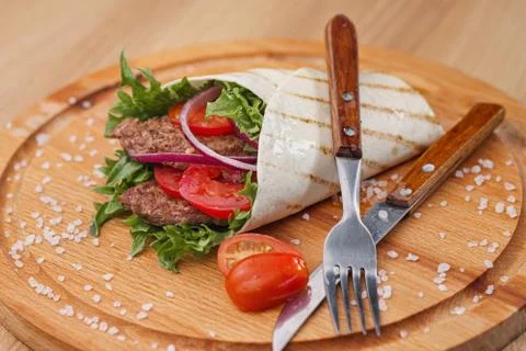 Beef roll, cooked on fire in a thin dough tortilla with vegetables and salad Stock Photos
