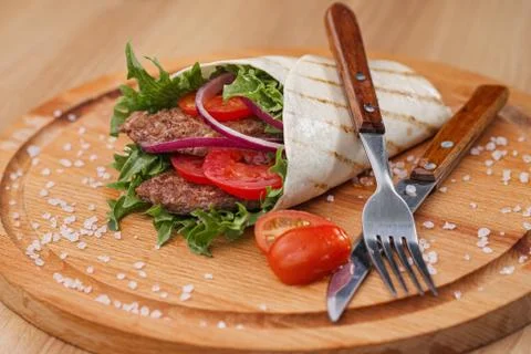 Beef roll, cooked on fire in a thin dough tortilla with vegetables and salad Foto stock