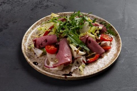 Beef salad in a plate on a dark background. Stock Photos