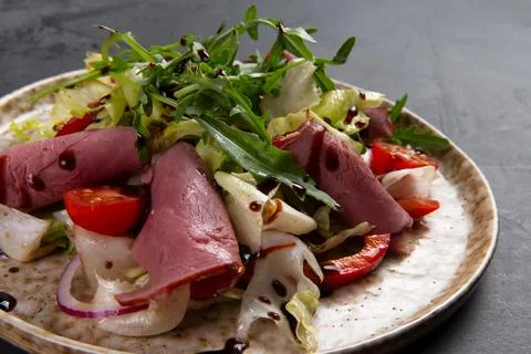Beef salad in a plate on a dark background. Stock Photos