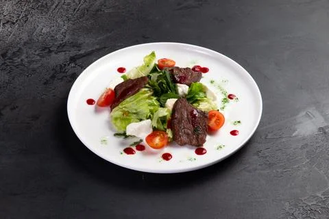 Beef salad in a plate. on a dark background. Stock Photos