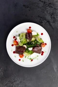 Beef salad in a plate. on a dark background. Stock Photos