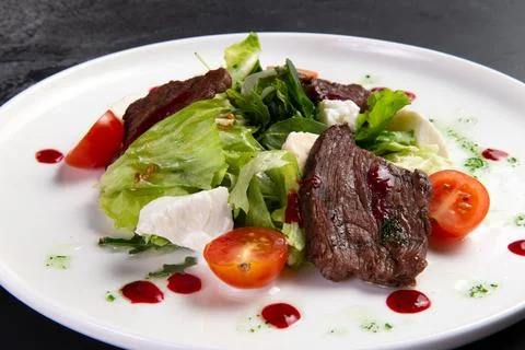 Beef salad in a plate. on a dark background. Stock Photos