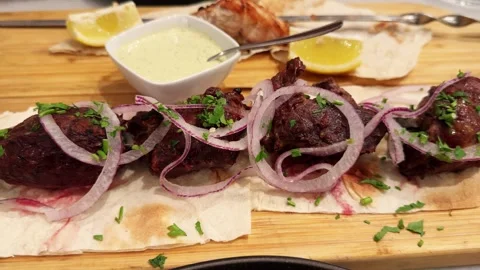 Beef shashlik, cooked over coals on pita bread, served with sauce, onion and Stock Footage 327900210