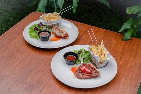Beef Steak and Beef Ham with French Fries, Fresh Salad, and Sauces on a Whi.. Stock Photos