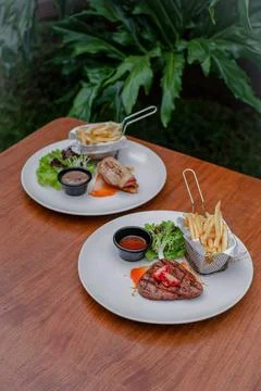 Beef Steak and Beef Ham with French Fries, Fresh Salad, and Sauces on a Whi.. Stock Photos
