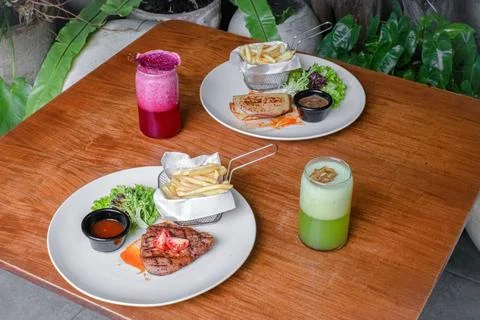 Beef Steak and Beef Ham with French Fries, Fresh Salad, and Sauces on a Whi.. Foto stock