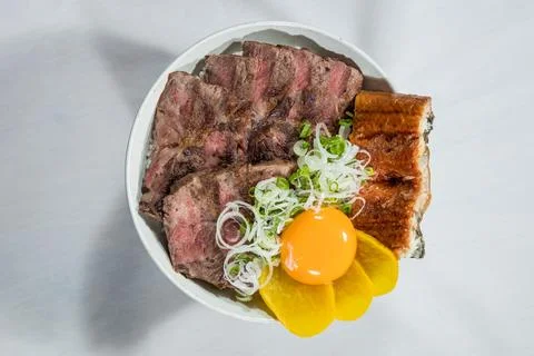 Beef steak and eel rice bowl with egg yolk Stock Photos