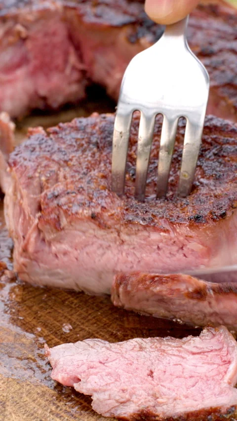 Beef steak being cut with knife and fork on board vertical video Stock Footage 330521670