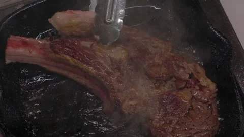 Beef steak is being turned over and fried in a broiler pan. Stock Footage 221496117