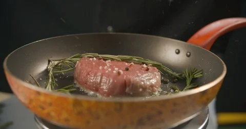 Beef steak is cooked in pan with sprigs of rosemary, salt and pepper Stock Footage 112280178