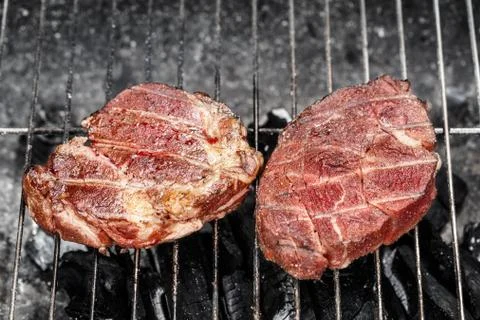 Beef steak cooking on a grill Stock Photos