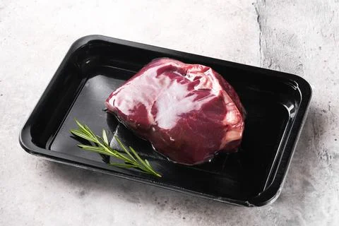 Beef steak. Fresh raw beef steak with fork and rosemary in vacuum black plast Stock Photos