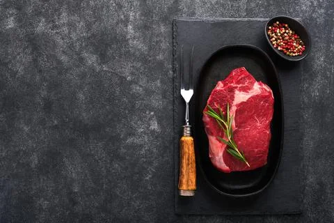 Beef steak. Fresh raw beef rib eye steak with fork rosemary, salt and pepper  Stock Photos