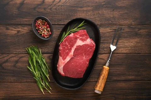 Beef steak. Fresh raw beef rib eye steak with fork rosemary, salt and pepper  Stock Photos