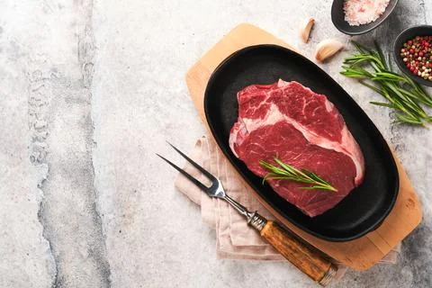 Beef steak. Fresh raw beef rib eye steak with fork rosemary, salt and pepper  Stock Photos