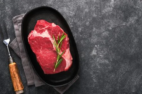 Beef steak. Fresh raw beef rib eye steak with fork rosemary, salt and pepper  Stock Photos