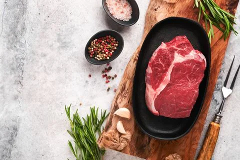 Beef steak. Fresh raw beef rib eye steak with fork rosemary, salt and pepper  Stock Photos