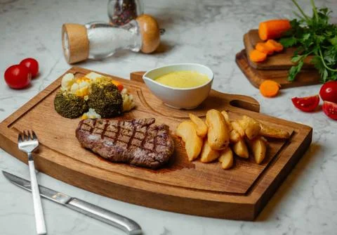Beef steak with fried potatoes, boiled brocolli, carrot, corn and sauce Stock Photos