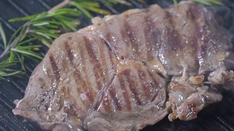 Beef steak on the grill is sprinkled with black pepper. Slow motion Stock Footage 75239355