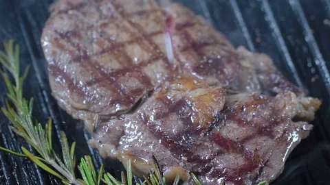 Beef steak on the grill is sprinkled with large sea salt. Slow motion Stock Footage 75239787