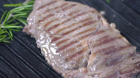 Beef steak on the grill is sprinkled with salt. Slow motion Stock Footage 75057397