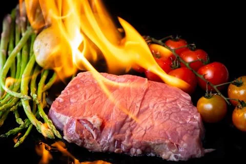 Beef steak grilling on back background Stock Photos