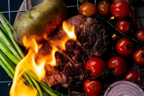 Beef steak grilling on back background Stock Photos
