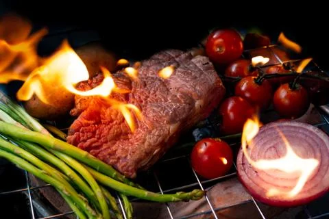 Beef steak grilling on back background Stock Photos