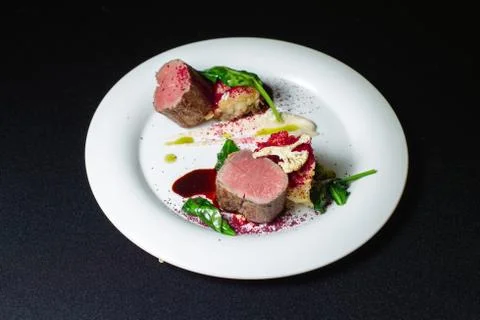 Beef steak with mashed potatoes decorated with greens on a white plate. Photos