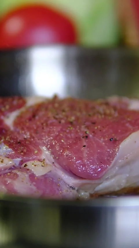 Beef steak placed into hot oil on stainless steel pan as chef tilts the pan for Stock Footage 346181328