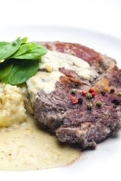 Beef steak with sauce, mashed potatoes and spinach leaves Stock Photos